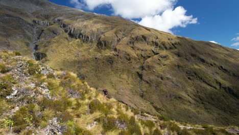 Woman-traveler-with-backpack-hiking-on-mountain-ridge-in-New-Zealand---aerial-drone