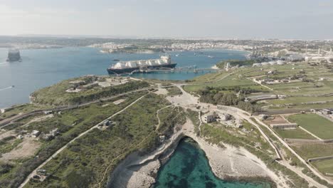 Aerial-drone-shot-from-afar-over-Kalanka-bay-Malta-towards-a-gas-tank-ship-in-Birzebbugia