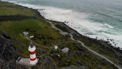 Aerial-of-lighthouse-located-on-rocky-cliffs,-cloudy-day