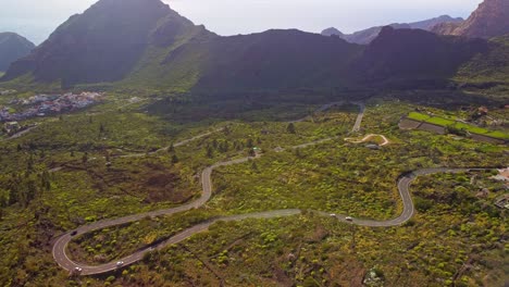 Panoramic-drone-shot-of-Tenerife-road-in-beautiful-scenic-lush-green-valley-of-Los-Gigantes-surrounded-by-mountains-in-morning,-featuring-holiday-destination-of-canary-island,-Spain