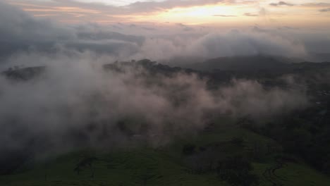 Drone-Flyover-Grassy-Mountain-Peak-Surrounded-By-Clouds-At-Sunset,-4K-Costa-Rica