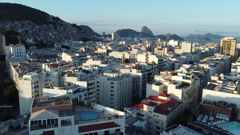 Beautiful-afternoon-in-Rio-de-Janeiro,-buildings-and-sea-landscape-with-sugar-loaf-and-birds-passing-in-slow-motion,-golden-hour-by-drone-aerial