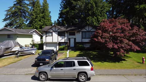 Ein-Atemberaubendes-Weißes-Einfamilienhaus-In-Brookswood,-Langley,-BC,-Kanada,-Mit-Einem-üppigen-Garten-Aus-Bäumen-Und-Gras,-Der-Von-Der-Umgekehrten-Luftaufnahme-Der-Drohne-Aus-Sichtbar-Ist