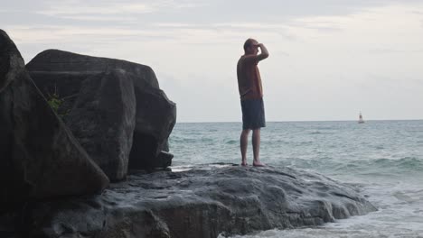 Hombre-Mirando-El-Mar-Mientras-Está-De-Pie-Sobre-La-Roca-En-La-Playa-De-Dam-Trau,-Vietnam