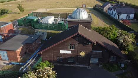 Aerial-view-Pex-hill-Leighton-observatory-silver-dome-rooftop-on-hilltop-farmland-at-sunrise,-tilt-down-rise