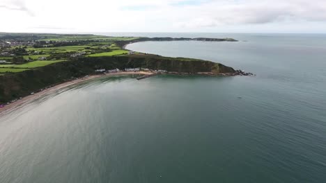 Aerial-view-approaching-the-harbour-and-beach-huts-at-Nefyn-with-Porthdinllaen-in-the-distance-situated-on-the-Llyn-Peninsula-in-North-Wales