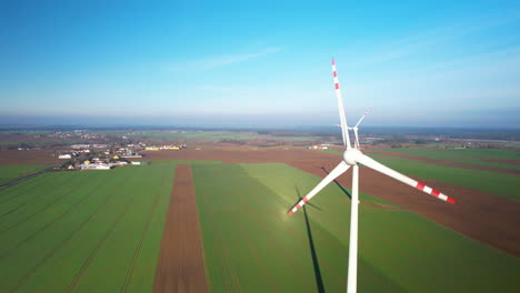 Aerial-rising-over-wind-turbines-spinning-on-large-towers-in-crops-farmland-in-Poland-countryside