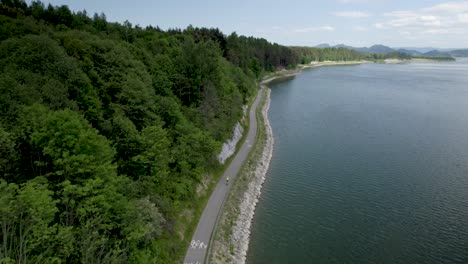 Drohnenaufnahme-Eines-Bikers,-Der-In-Atemberaubender-Landschaft-Am-See-Entlang-Fährt