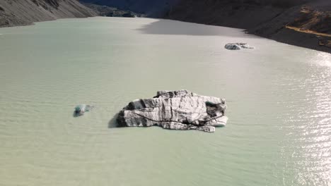 Iceberg-in-Hooker-Lake-aerial-reveal-of-Aoraki---Mt-Cook,-New-Zealand