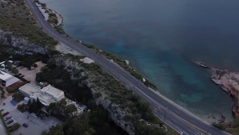 Diagonal-aerial-footage-above-Athenian-riviera-|-Highway-by-the-sea-in-Vouliagmeni-area-in-Athens-near-lake-Vouliagmeni-|-4K
