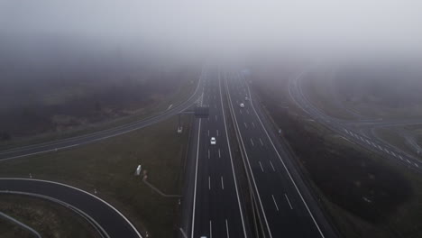 Backwards-aerial-flight-in-cloudy-weather-tilting-down-on-German-highway-with-driving-white-cars-in-autumn-season