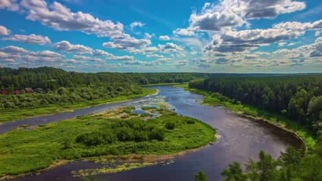 Timelapse-shot-of-river-flowing-on-both-sides-of-a-small-island-surrounded-by-lush-green-vegetation-on-a-cloudy-day