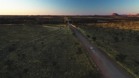 Drone-shot-tracking-a-4x4-driving-in-distant-nature,-sunset-in-Namibia,-Africa