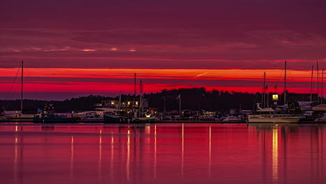 Luxury-boats-and-cityscape-during-red-sunset-sky,-time-lapse-view