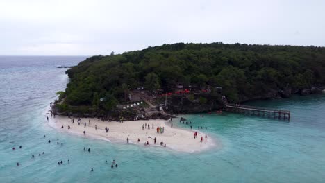 Aerial-view-perspective-of-the-Sumilon-island-white-sandbar-beach,-with-tourists-swimming-in-tropical-clear-water,-a-small-resort-island-in-open-sea-near-oslob-in-Cebu-philippines