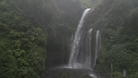 Tourist-man-uses-selfie-stick-camera-in-mist-below-Tiu-Kelep-waterfall