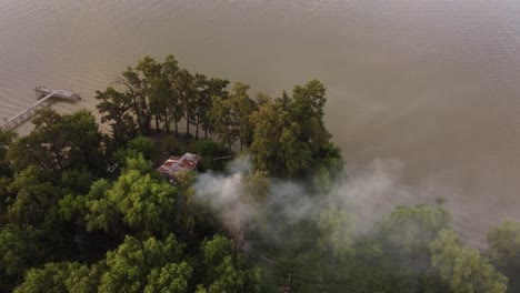 Tilt-Down-Shot-Of-Fire-Starting-At-Amazon-Forest-Near-River-Shore