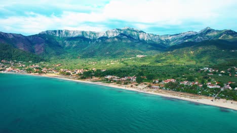 Aerial-View-Of-Golden-Beach-With-Towering-Mountain-Peaks,-Beautiful-Beachfront-And-Lush-Green-Vegetation,-Vivid-Colors,-Thassos-Island,-Greece,-Europe