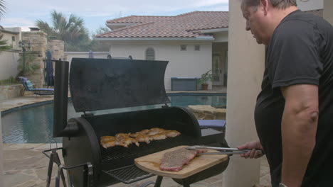 Man-puts-rack-of-BBQ-ribs-on-to-hot-grill-in-his-back-yard