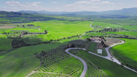 Olive-tree-plantations-and-green-fields-in-Tuscany,-wide-forward-drone