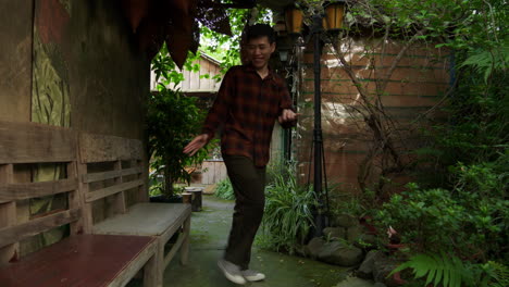 Positive-asian-man-practicing-freestyle-dance-steps-in-a-tropical-garden