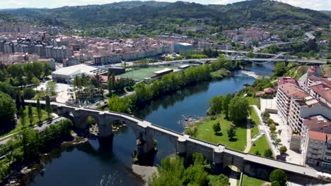 Mino-river-flowing-through-Ourense,-ancient-and-modern-bridge,-aerial