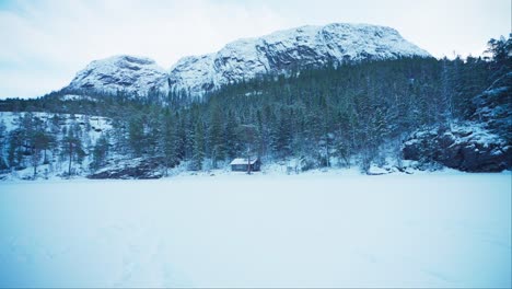 Impresionante-Paisaje-Invernal-Con-Cabaña-Aislada-Debajo-De-La-Montaña-Del-Bosque-Cubierto-De-Nieve