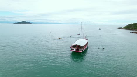 Aerial-orbit-of-tourist-boat-on-the-Tartaruga-beach-shoreline,-Brazil