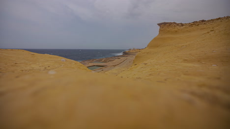 Ocean-waves-break-on-salt-pans-of-northern-island-in-Malta,-timelapse