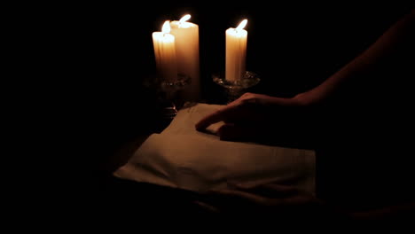 Holy-Bible-Being-Read-by-Candle-Light-in-a-Hidden,-Dark-Place