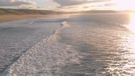 Die-Atemberaubende-Luftaufnahme-Von-Perran-Sands-Bei-Sonnenuntergang,-Die-Wellen-Sind-Ruhig-Und-Es-Liegt-Eine-Heitere-Atmosphäre-In-Der-Luft