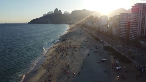 Sunset-at-Arpoador-beach-in-Rio-de-Janeiro,-golden-light-moment-by-drone-aerial-shot,-sea-and-mounts