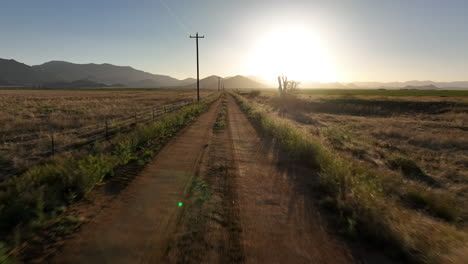 POV-shot-of-driving-down-a-rural-dirt-road-into-the-sun