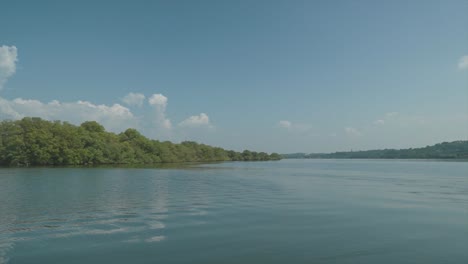 POV-Aufnahme-Einer-Bootsfahrt-Mit-Ruhigem-Blauen-Wasser-Und-Grünen-Bäumen,-Die-Eine-Ruhige-Landschaft-Schaffen