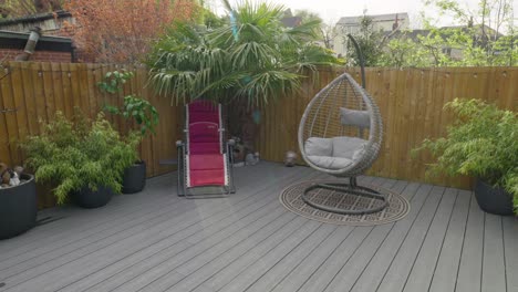 Minimalistic-UK-summer-garden-showing-swing-chair-decking-and-sun-lounger