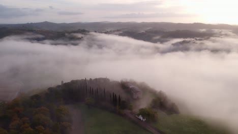 Tuscany-hill-landscape-covered-in-thick-morning-mist,-aerial
