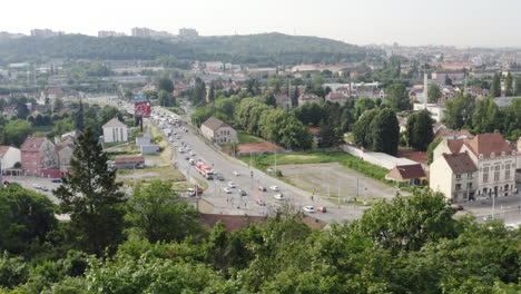 Car-traffic-on-city-street-in-Brno-behind-tree-greenery,-Czechia