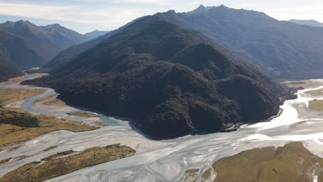Spectacular-aerial-view-of-green-mountain-in-glacier-river-valley,-West-Coast,-New-Zealand