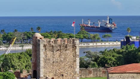 Luftaufnahme-Der-Festung-Ozama-Mit-Wehender-Flagge-Und-Altem-Schiff-Auf-Dem-Meer-Im-Hintergrund---Santo-Domingo,-Dominikanische-Republik