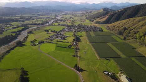 Beautiful-aerial-view-of-Motueka-Valley,-Tapawera-town,-river-and-mountains-on-horizon,-New-Zealand