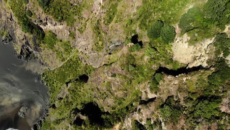 drone-reveal-mountain-crest-cliff-rock-formation-on-the-coastline-of-Comans-Track,-Karekare,-New-Zealand-aerial-landscape-wild-nature-paradise