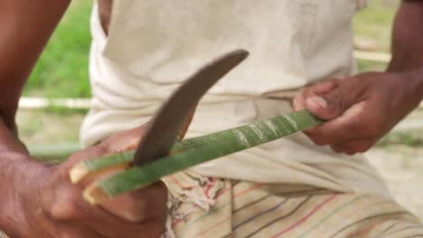 close-up-of-asiatic-artisan-using-a-sharp-knife-for-cutting-bamboo-stick-for-artisan-product