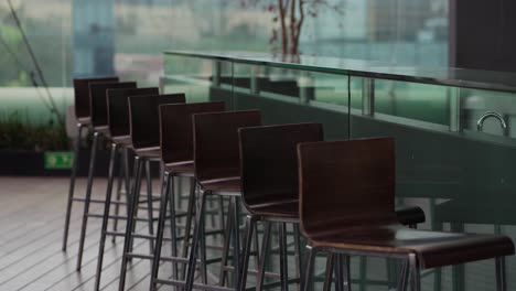 Bar-stools-beautifully-arranged-in-front-off-glass-top-bar,-medium-shot