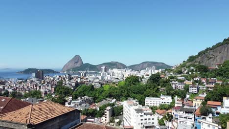 Reveal-of-Rio-de-Janeiro-Landscape---Favela,-buildings,-sea-and-Pao-de-Acucar-on-the-background---daylight-landscape-by-drone