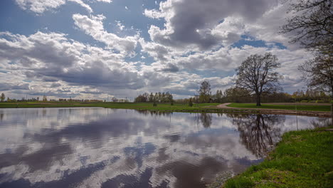 White-clouds-float-by-over-a-lake-in-a-green-setting