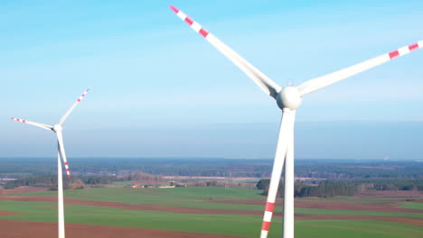 Nahaufnahme-Einer-Drohnenaufnahme-Rotierender-Weißer-Windmühlen-In-Ländlichen-Gebieten-Bei-Blauem-Himmel-In-Der-Natur