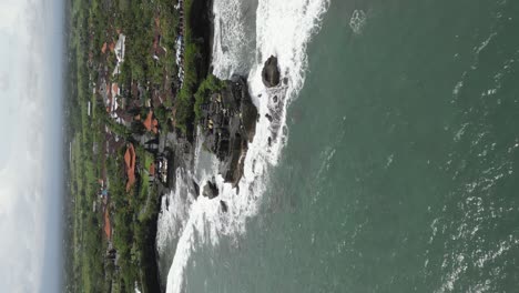 Vertical-format-aerial:-Tanah-Lot-Temple-on-rugged-rocky-Bali-coast