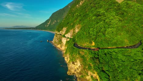 Aerial-view-of-vibrant-coastline-with-green-mountains-and-coastal-road-in-front-of-blue-ocean-in-Taiwan