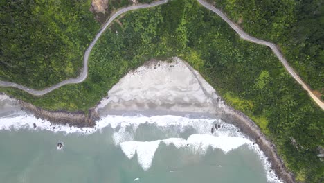 Amazing-birds-eye-view-of-sandy-beach-and-winding-road-surrounded-by-native-jungle