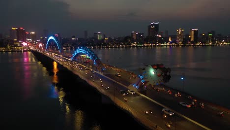 Erstaunliche-Farbenfrohe-Luftaufnahme-Der-Drachenbrücke-Cau-Rong,-Des-Verkehrs-Und-Der-Skyline-Der-Stadt-Bei-Nacht-In-Danang,-Vietnam
